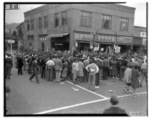 Black and white photo of large group at Sather Gate on UC Berkeley campus gathered around a speaker who cannot be seen over the crowd.